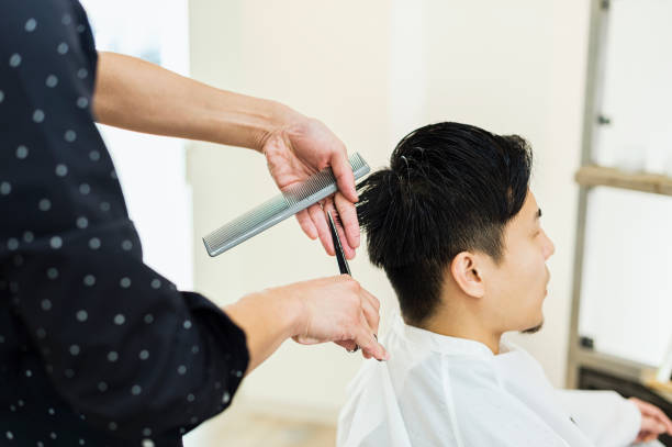 jonge volwassen mannelijke hair stylist eigenaar snijden man's haar - hairstyle stockfoto's en -beelden