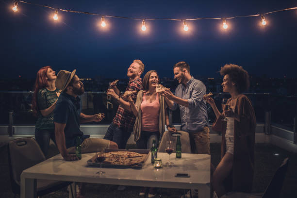 joyful friends having a dinner party during the night on a terrace. - junk food stock pictures, royalty-free photos & images