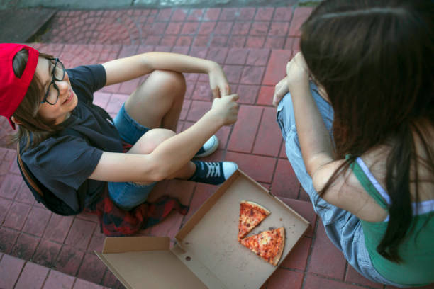 joyful, happy friends eating pizza outside - junk food stock pictures, royalty-free photos & images