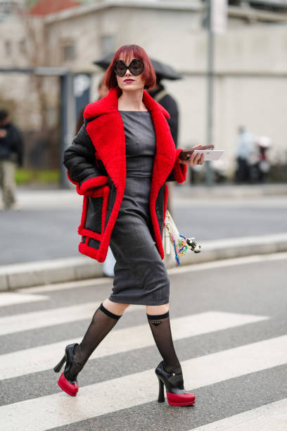 Julia Hobbs Dag wears black sunglasses, dark gray fitted midi dress, black bright cherry red aviator coat, black sheer mesh Prada compression socks,...