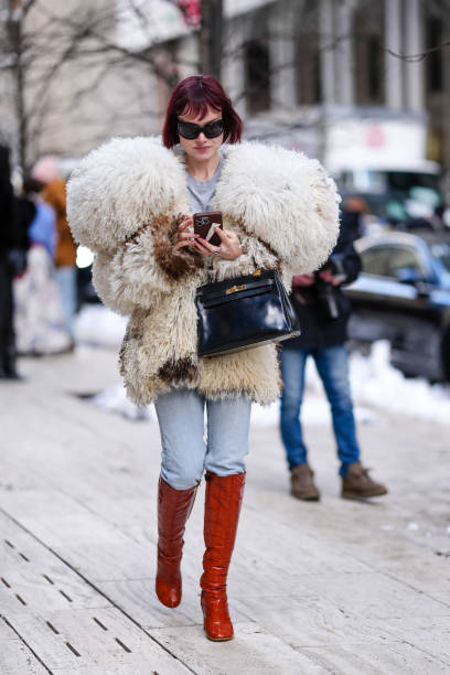 Julia Hobbs wears black sunglasses, light gray t-shirt, faux fur Alexander Mcqueen coat, shiny black Hermes Kelly leather shoes, light blue skinny...