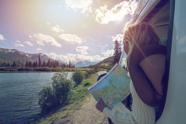 junge frau schaut fahrplan in der nähe von bergsee - travel stock-fotos und bilder