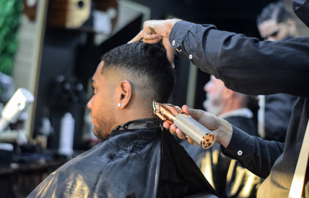 junger mann mit einem haarschnitt in einem friseurgeschäft - hairstyle stock-fotos und bilder