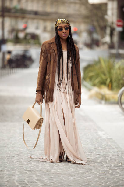 Karen Blanchard wears beige long maxi dress with slits, brown suede jacket with tassels, yellow bandana, sunglasses and beige bag outside the Akris...