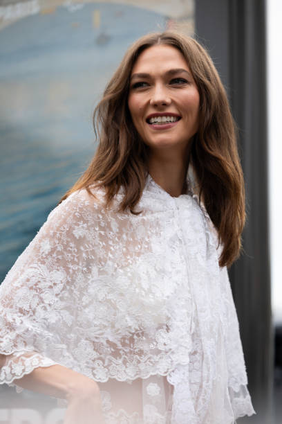 Karlie Kloss wears a white see-trough lace shirt outside Chloé show during Womenswear Spring/Summer 2025 as part of Paris Fashion Week on September...