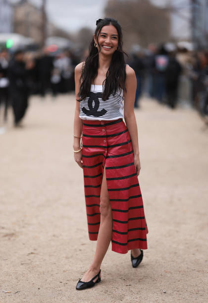 Kelsey Merritt seen wearing a black and white striped Chanel top, black and red striped long skirt, black Chanel ballerinas and a mini brown and...