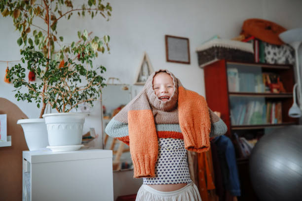 kid girl dresses herself in warm hand-knitted sweater at home. real-life micromoments. - fashion stock pictures, royalty-free photos & images