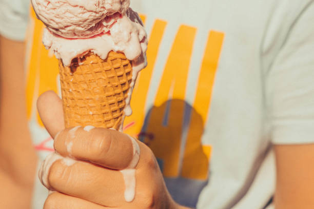 kid holding ice cream cone melting in hot summer. - food stock pictures, royalty-free photos & images