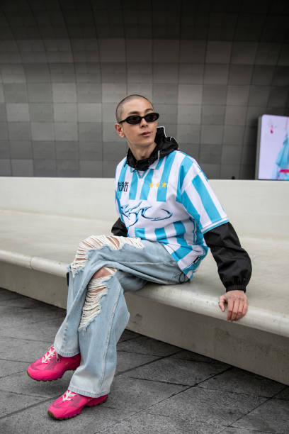 Kim Seong-ju wears a blue striped soccer jersey from Ajobyajo and pink sneakers from Nike x Jaquemus at Seoul Fashion Week AW 23 on March 17, 2023 in...