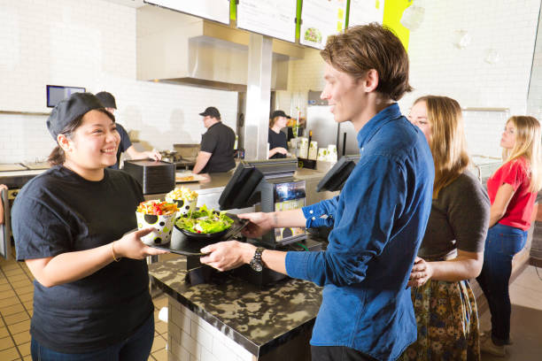 kitchen and wait staff serving customers in fast food restaurant - junk food stock pictures, royalty-free photos & images