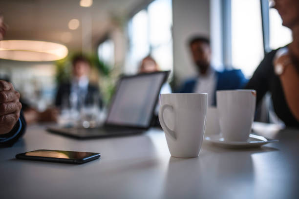 koffie mokken en smart phone op vergadertafel - coffee stockfoto's en -beelden