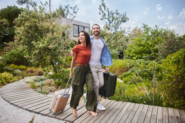 lächelndes paar, das mit koffern in seiner ferienunterkunft ankommt - travel stock-fotos und bilder