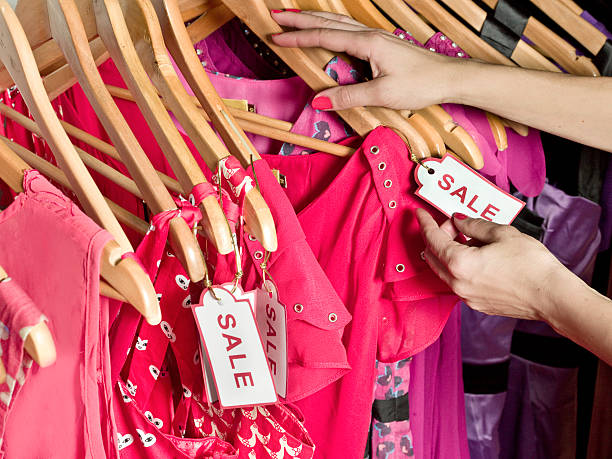 lady picking out dresses with a sale tag on it - fashion stock pictures, royalty-free photos & images