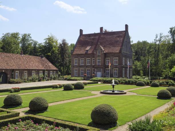 large manor house with magnificent gardens and fountain, framed by trimmed bushes and manicured lawn, ochtrup, münsterland, germany - garden decoration stockfoto's en -beelden
