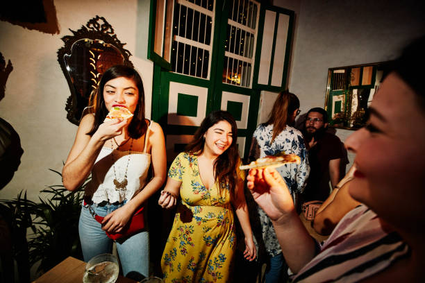 laughing female friends enjoying food during party in night club - fashion stock pictures, royalty-free photos & images