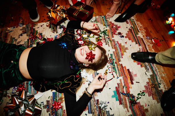 laughing woman lying on floor with bows over eyes during holiday party with friends - home decoration stock pictures, royalty-free photos & images