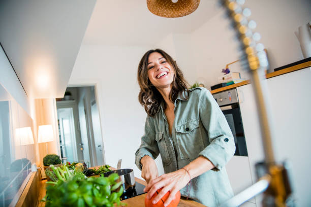 laughing woman slicing pumpkin in her kitchen - food stock pictures, royalty-free photos & images