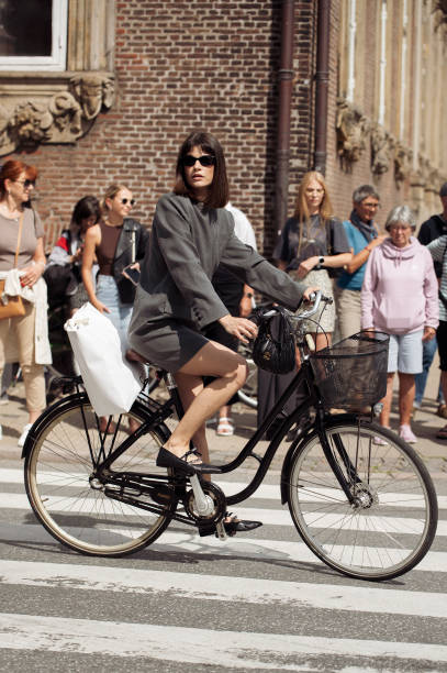Lea Naumann riding a bicycle wears grey long sleeve mini dress and black shoes outside the Gestuz show during day four of the Copenhagen Fashion Week...