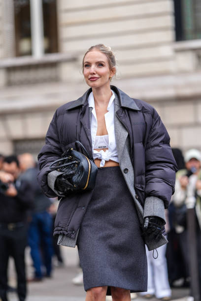 Leonie Hanne wears white Miu Miu bralette, white buttoned up long sleeve tied shirt, dark gray Miu Miu blazer jacket, black high waisted Miu Miu over...