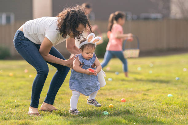 liebende mutter hilft entzückende kleinkind tochter mit ostereiersuche im freien - garden decoration stock-fotos und bilder