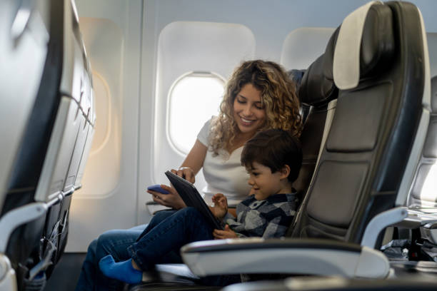 liebende mutter und sohn spielen mit tablet während eines fluges sieht sehr glücklich - travel stock-fotos und bilder
