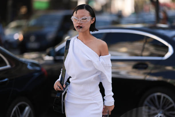 Lin Lin is seen wearing a black Puma x Ottolinger bag, a white dress, transparent shades and a silver ornament around her mouth before the Ottolinger...