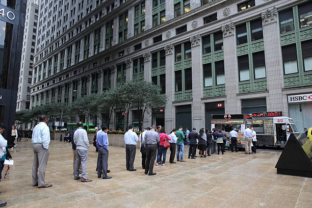 Line of lunch time customers at a mobile street vendor selling food in the business district in downtown Manhattan, New York City, USA. 16th...