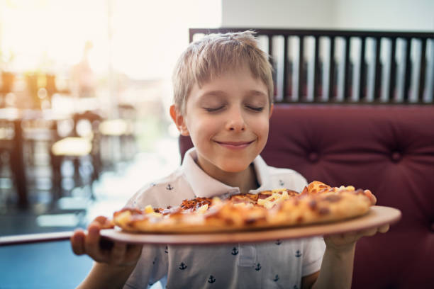 little boy smelling pizza in restaurant - food stock pictures, royalty-free photos & images