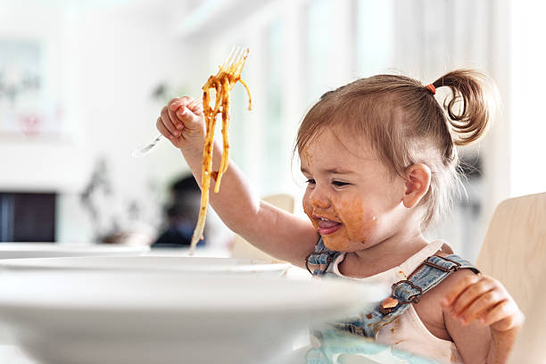little girl 2 years old girl eating noodles - food stockfoto's en -beelden