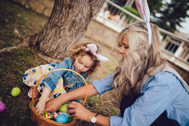 little girl and grandmother during easter egg hunt in park - garden decoration stock pictures, royalty-free photos & images