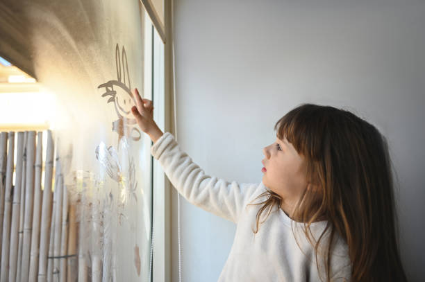little girl drawing on a fog window. - home decoration stock pictures, royalty-free photos & images
