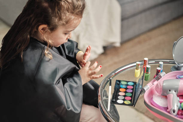 little girl is removing the paint from her nails - nails art photos et images de collection