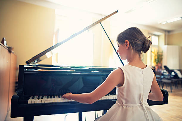 little girl playing on grand piano - concert stock pictures, royalty-free photos & images
