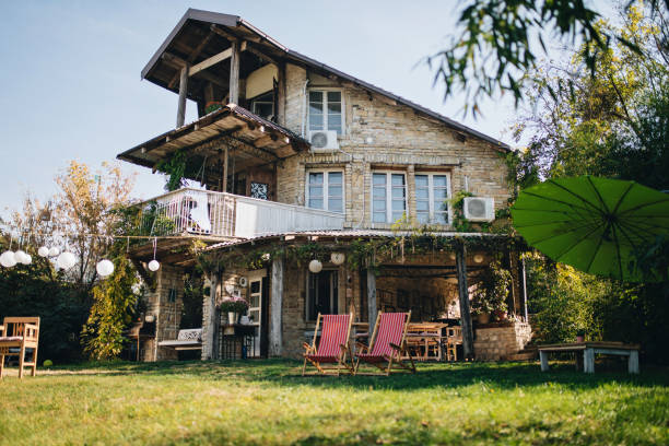 lovely stone house with a big front yard and a porch swing - garden decoration stock pictures, royalty-free photos & images