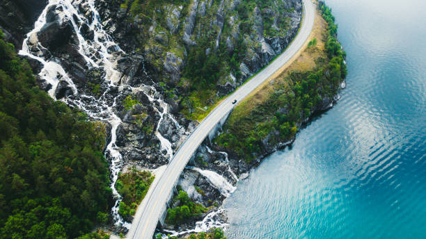 luftaufnahme der malerischen bergstraße mit auto, meer und wasserfall in norwegen - travel stock-fotos und bilder