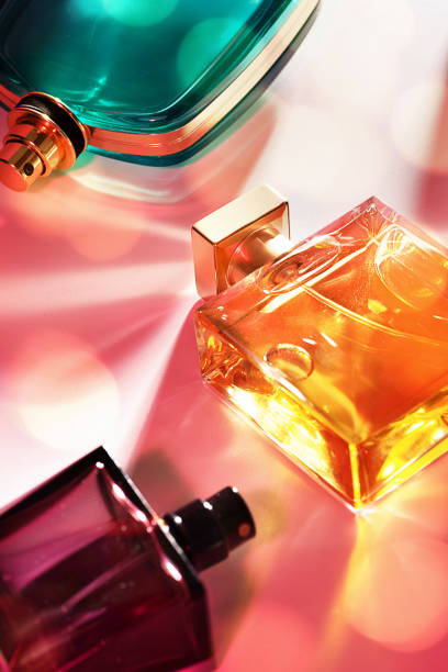 make-up cosmetic products for a women and men - set of perfumes in glass bottles with caustic light effect on pink color background with shadow from sunlight. - fashion stock pictures, royalty-free photos & images