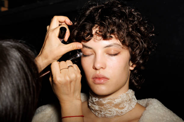 Makeup artist applies makeup to a model backstage at the Ermanno Scervino fashion show during the Milan Fashion Week - Womenswear Fall/Winter...