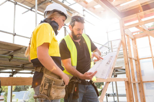 male and female construction workers discuss the building plans inside the building site - home decoration stock pictures, royalty-free photos & images