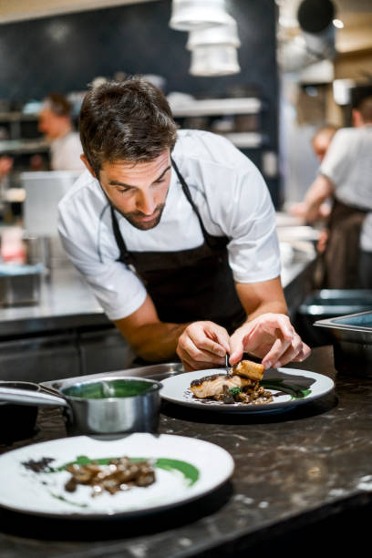 male cook preparing food in commercial kitchen - food stock pictures, royalty-free photos & images