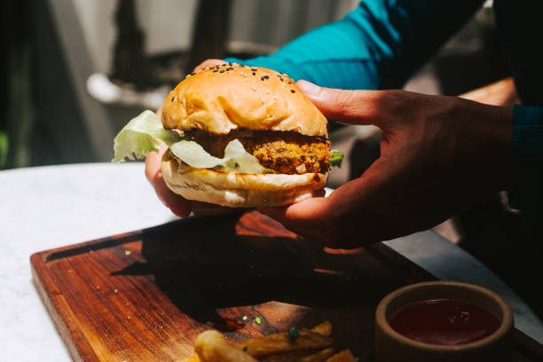 male hands holding vegan burger with bean patty - junk food stock pictures, royalty-free photos & images
