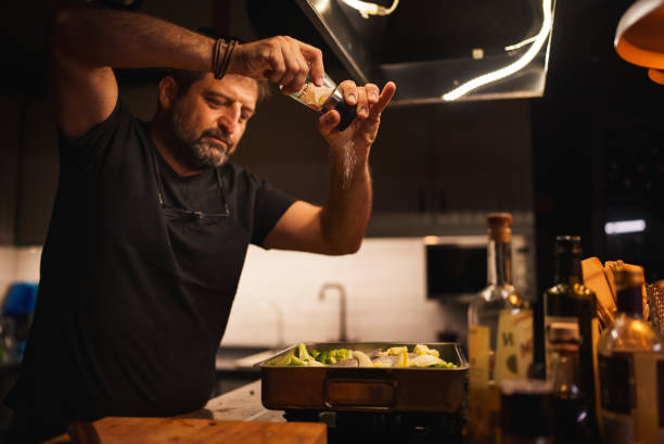 man adding spice from the salt grinder to the food - food stock pictures, royalty-free photos & images