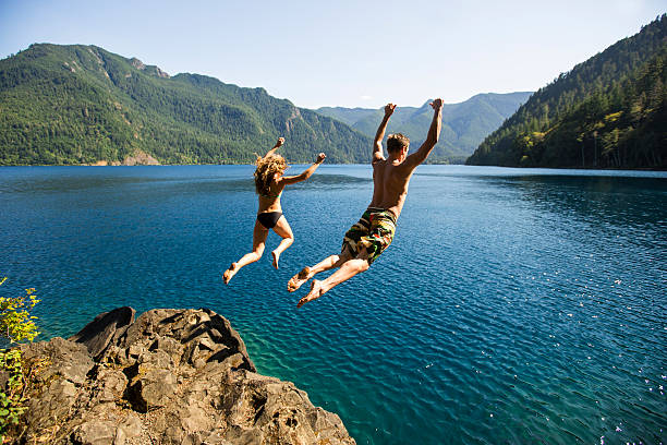 man and woman cliff jumping - travel stock pictures, royalty-free photos & images