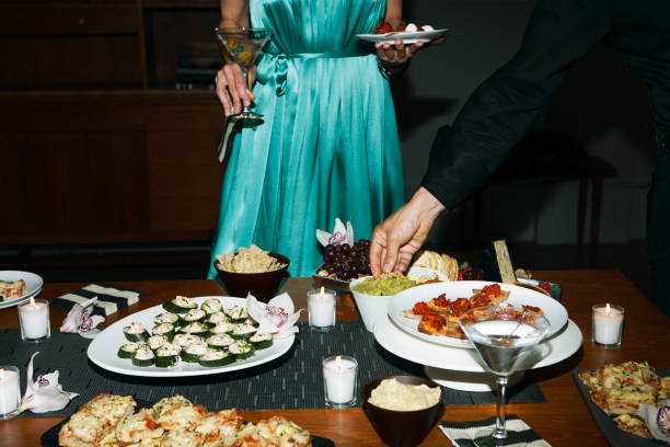 man and woman eating appetizers at cocktail party - food stock pictures, royalty-free photos & images