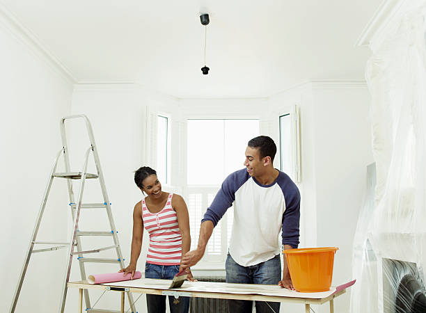 man and woman preparing to hang wallpaper - home decoration stock pictures, royalty-free photos & images