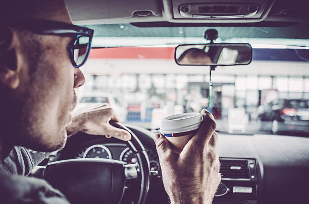 man driving his car and drinking take away coffee - junk food stock pictures, royalty-free photos & images