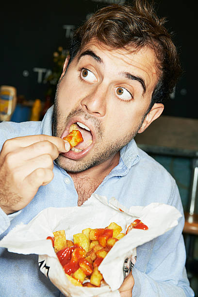 man eating bag of chips - food stock pictures, royalty-free photos & images