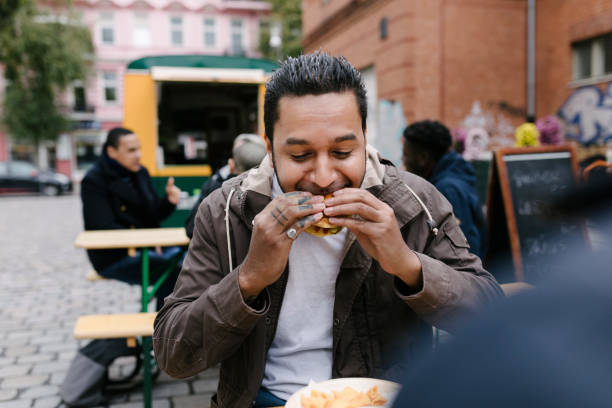man eating burger from food truck - food stockfoto's en -beelden