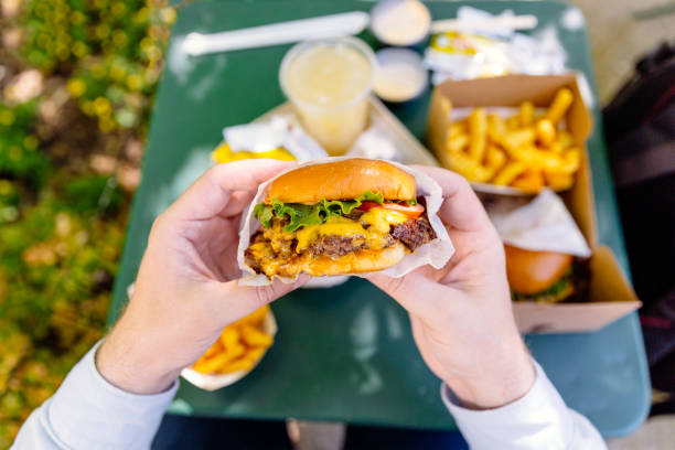 man eating cheeseburger, personal perspective view - junk food stock pictures, royalty-free photos & images