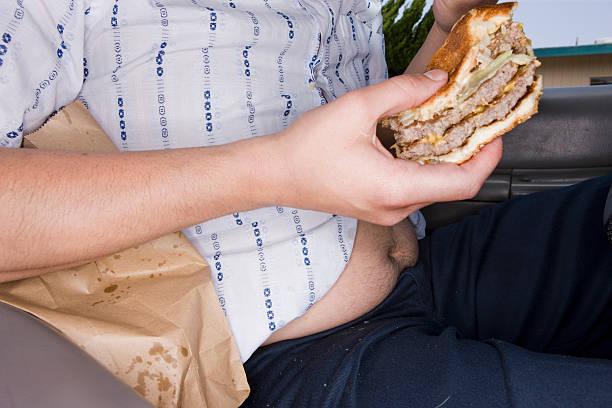 man eating fast food in his car - junk food stockfoto's en -beelden