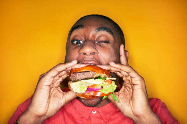 man eating hamburger - junk food stock pictures, royalty-free photos & images